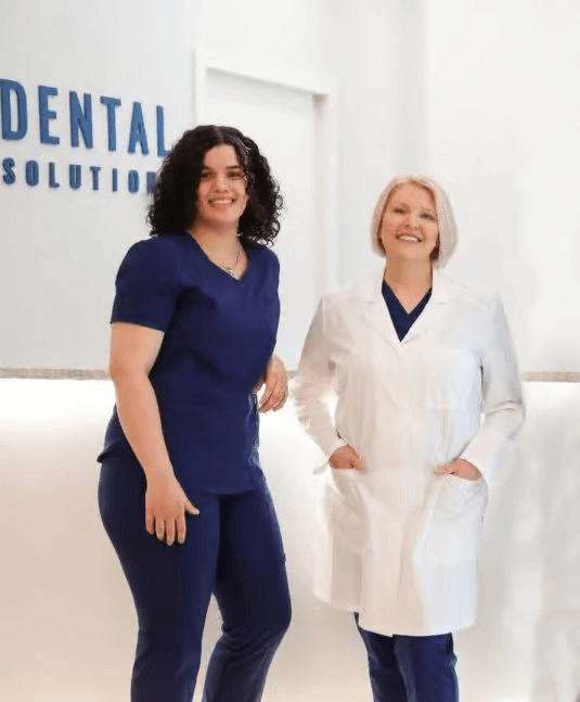 Two dental professionals smiling in clinic, dental care, healthcare team, modern dentistry, blue scrubs, white coat, dentist office.